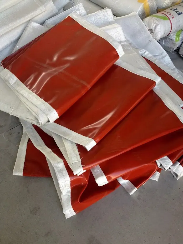 On-site replacement of a worn expansion joint fabric skin (joint skin) on a flue gas duct — old degraded belt removed, new composite fabric belt being installed on the existing steel frame